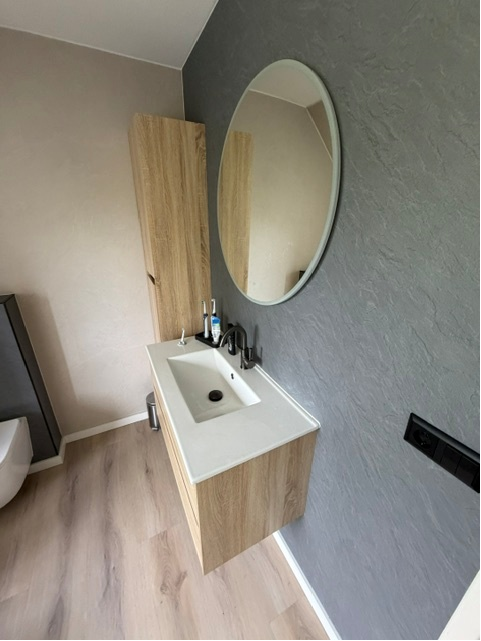 Houtlook badkamermeubel met zwarte kraan en ronde spiegel