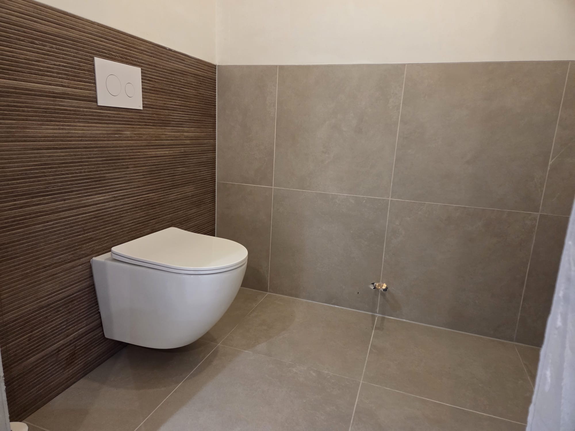 Hangtoilet met een warme wandafwerking en grote tegels