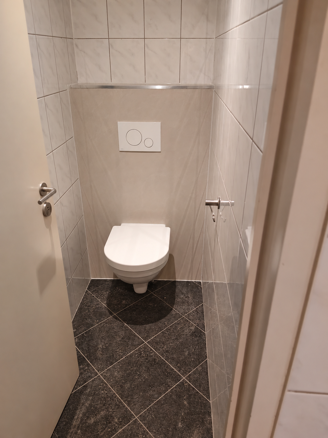 Vernieuwd hangtoilet met lichte wandtegels en donkere vloertegels bij Tapas & Zo